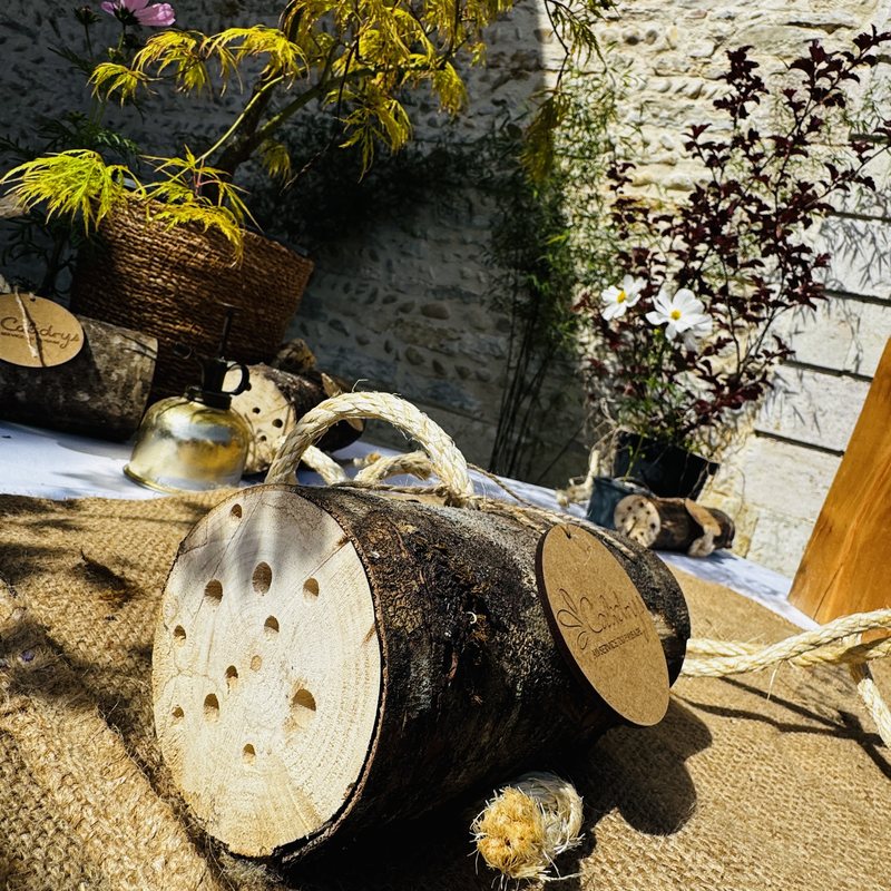 Hôtel à insectes en rondin sur table en jute